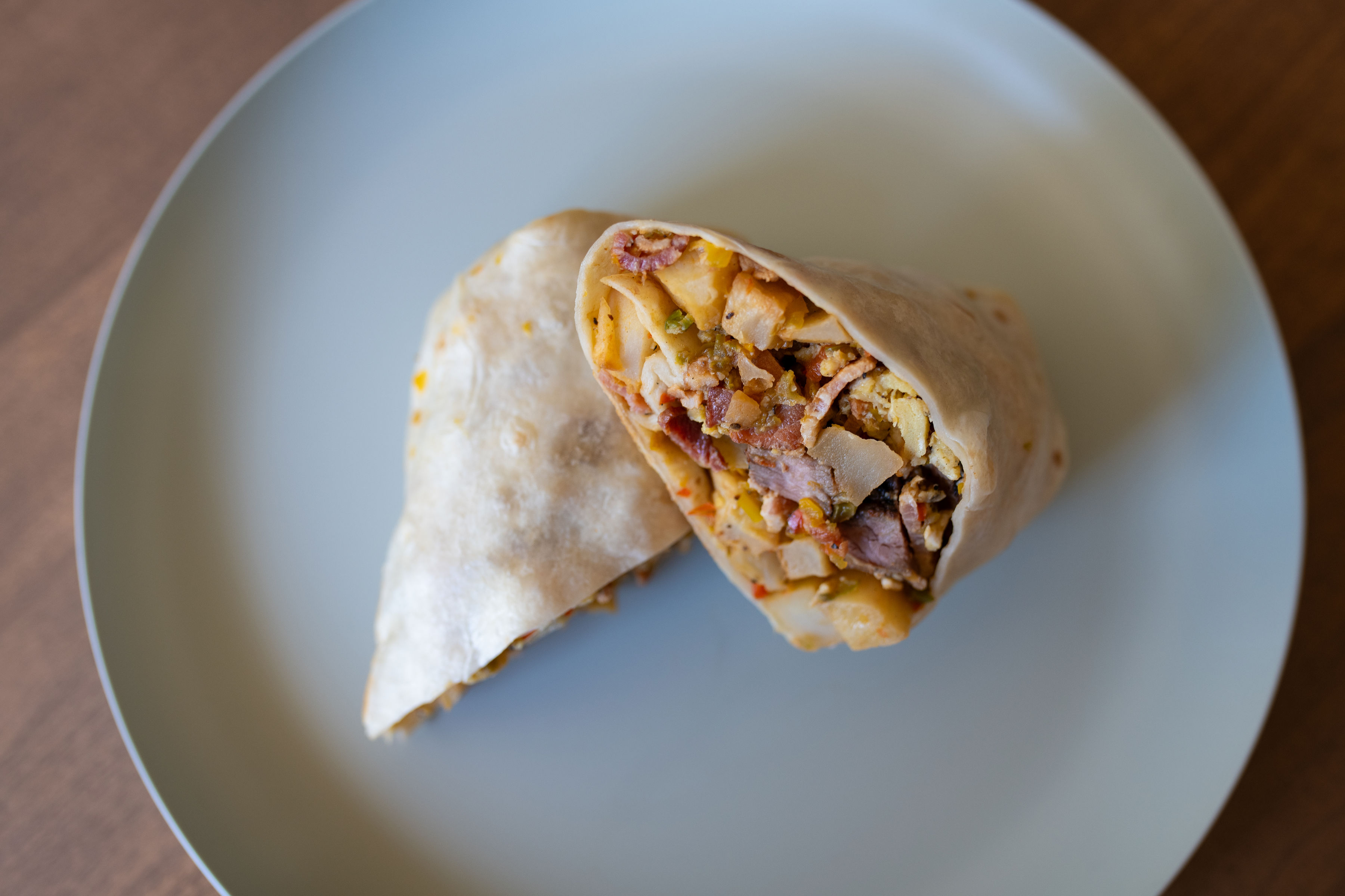 Breakfast burrito filled with steak, bacon, scrambled eggs, seasoned potatoes, and sautéed bell peppers